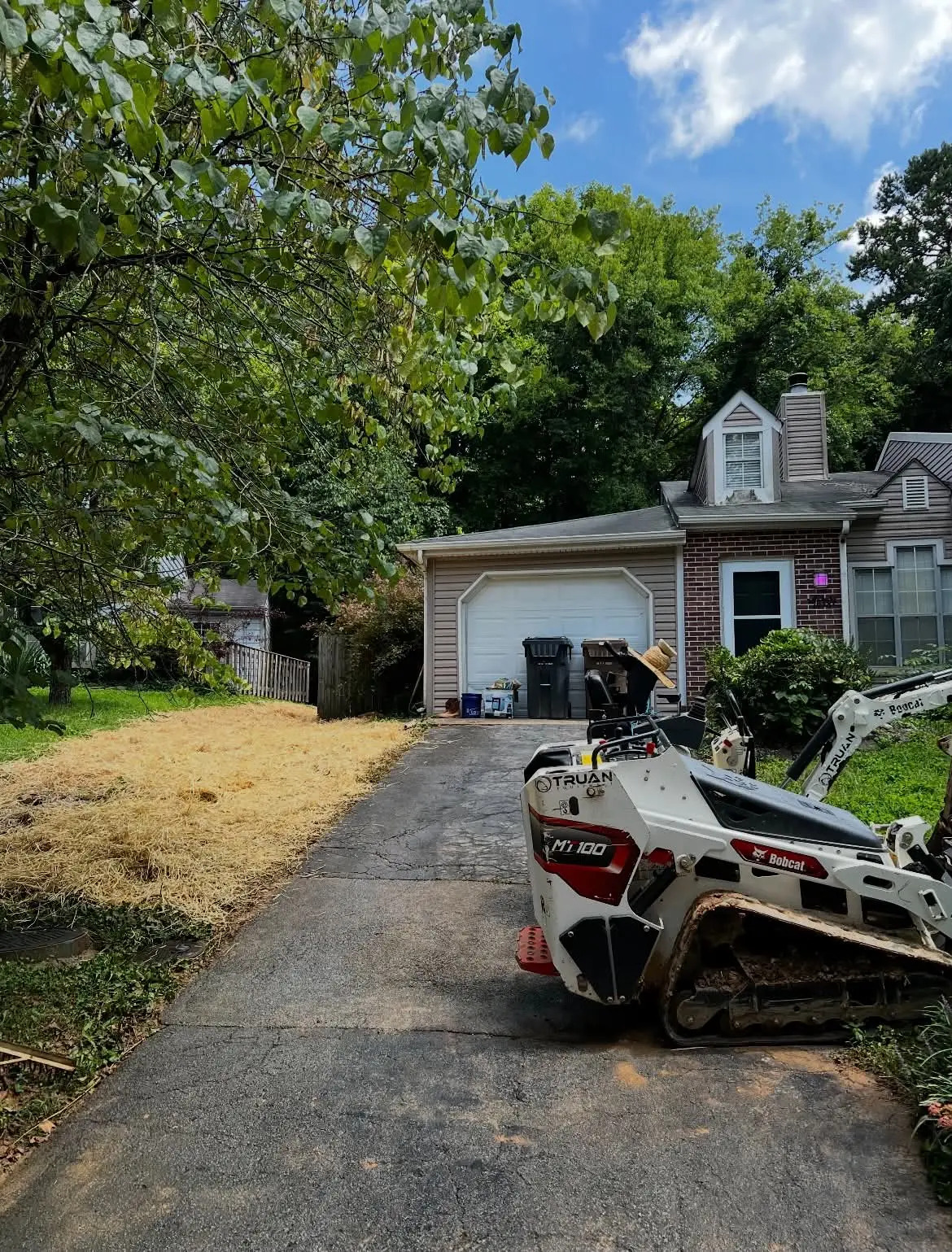 Skid steer parked in driveway after slope and property drainage restoration work