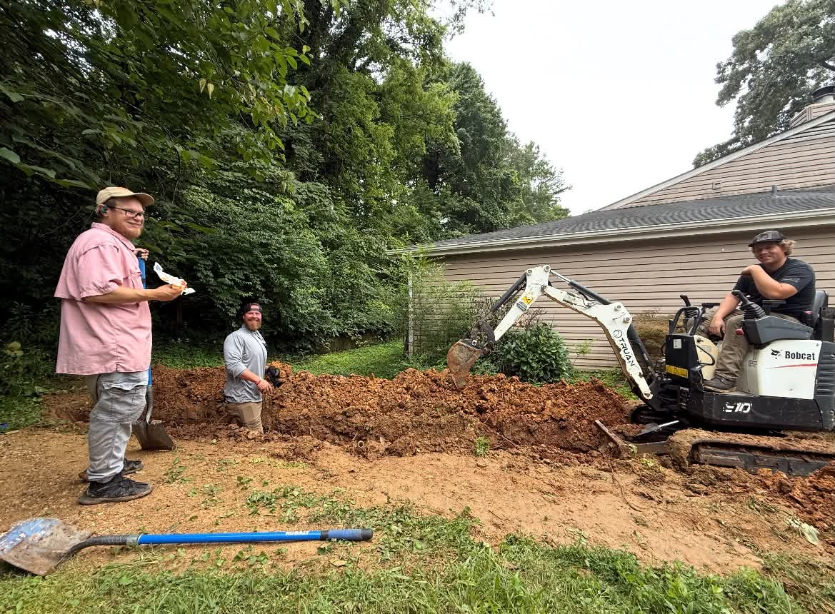 Crew working beside mini excavator during backyard drainage restoration project