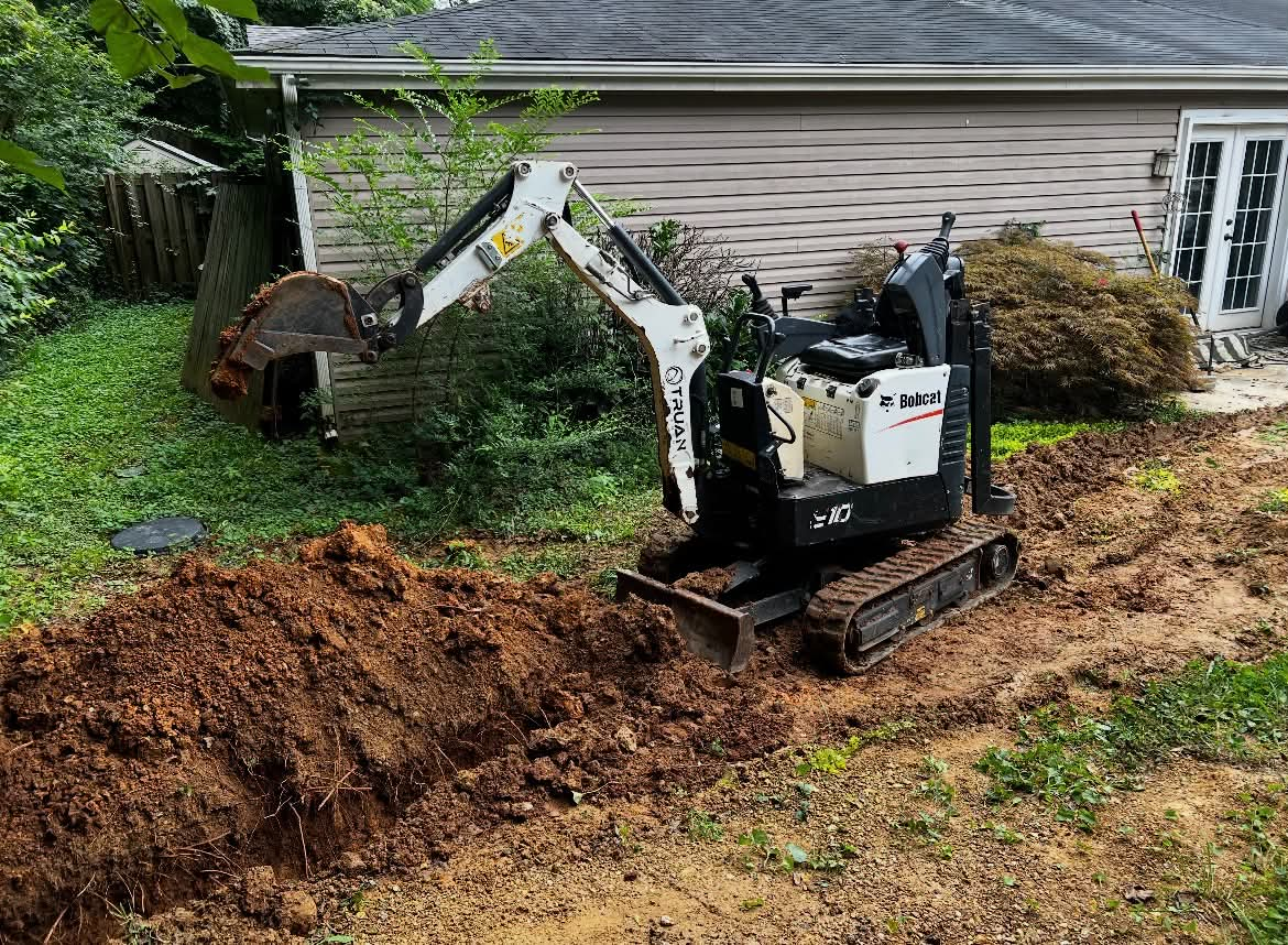 Bobcat mini excavator working dirt for drainage and grading job