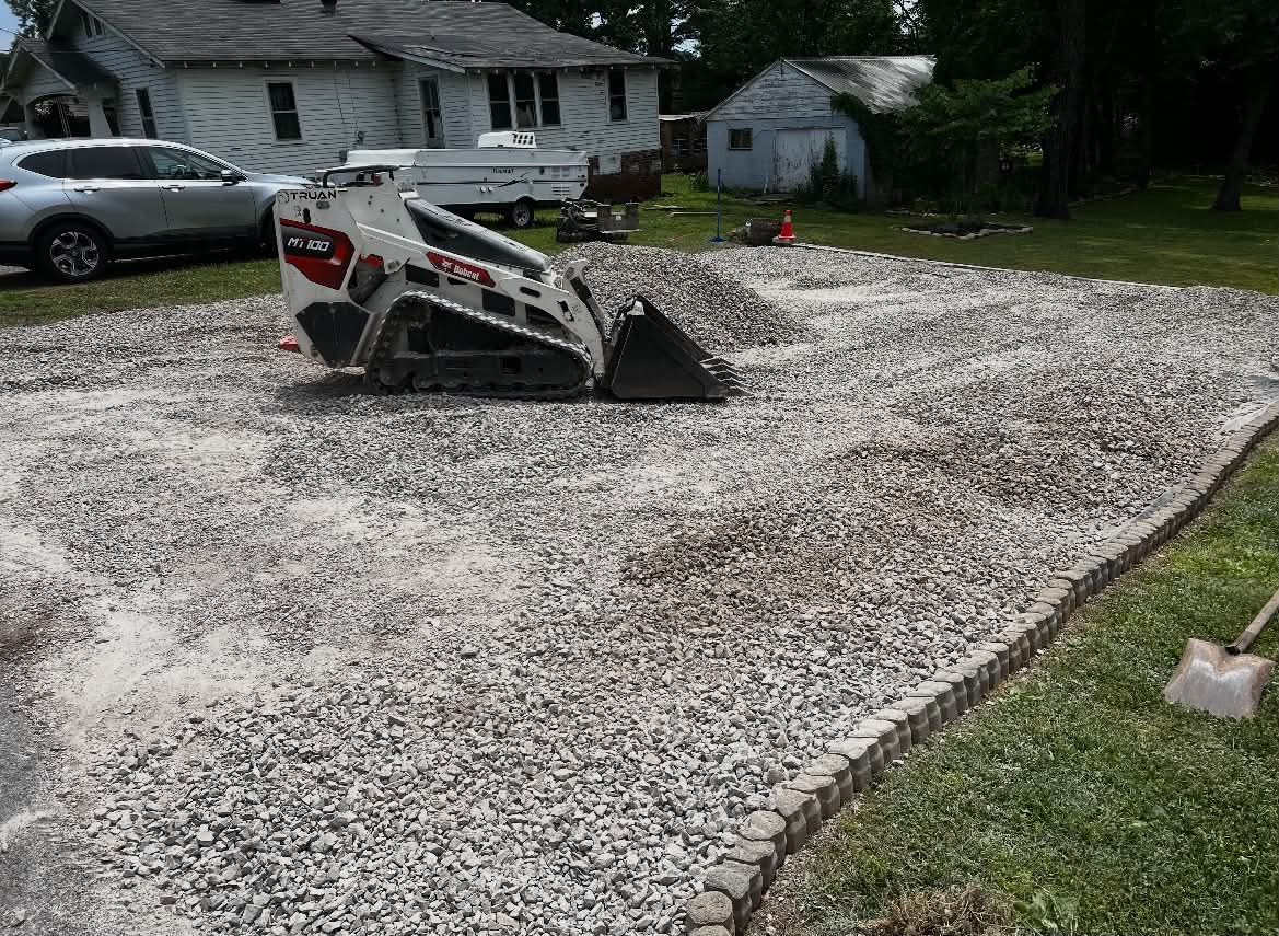 Bobcat spreading fresh gravel during driveway restoration